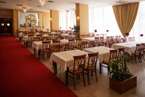 un ristorante con tavoli e sedie bianchi e un tappeto rosso di Hotel San Terme Laktaši a Laktaši