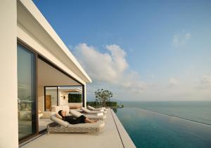 a man laying on a couch on the balcony of a house at Cape Azure Resort Samui by Thalsea in Plai Laem