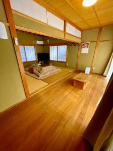 a large room with a bed and a wooden floor at 古民家宿誠makoto in Tamano