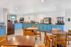 a kitchen with blue cabinets and wooden tables and chairs at Country Inn & Suites by Radisson, Georgetown, KY in Georgetown
