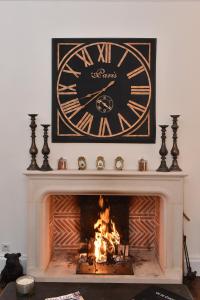 a clock is above a fireplace with a fire at Villa des Glycines in Thouars