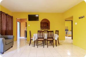 a dining room with a table and chairs and a couch at Enchanted Guest House & Hostel in Ocho Rios