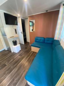 a living room with a blue couch and a television at Camping Mayotte, Biscarosse in Biscarrosse