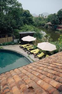 a swimming pool with two umbrellas and chairs and tables at Trang An Ninh Binh Rustic Hideaway in Ninh Binh