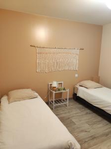 a bedroom with two beds and a table with a window at l'Echappée Crançotine in Crançot