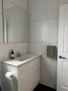 a white bathroom with a sink and a mirror at Happy Mountain House in Blackheath