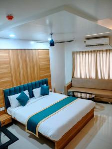 a bedroom with a large bed with blue pillows at Hotel Lotus Suites in Miraj