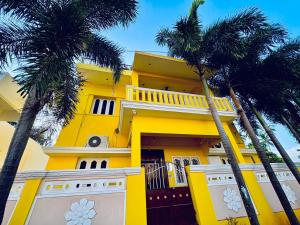 a yellow house with palm trees in front of it at Neon Villa in Pondicherry