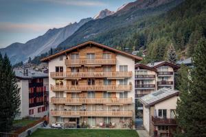 un gran edificio de apartamentos con balcones y una montaña en Ferienhaus Matterhorngruss, en Zermatt