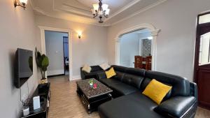 una sala de estar con un sofá de cuero negro y un televisor en Yoyo Celestial Home, en Arusha