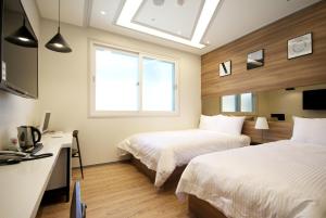 a bedroom with two beds and a desk with a computer at If Business Hotel in Changwon