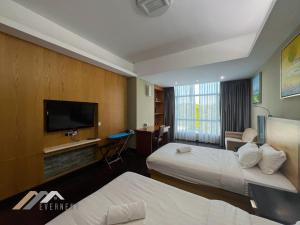a hotel room with two beds and a flat screen tv at Evernent Meritz in Miri