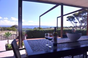 a table with two glasses of wine on a patio at The Rusty Kangaroo Hideaway - Ocean-View - Full Booking Service, Ferry, Experiences, Tour Option in Penneshaw