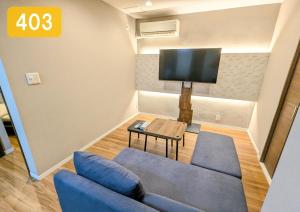 a living room with a blue couch and a tv at Chateau Sunrise in Tokyo