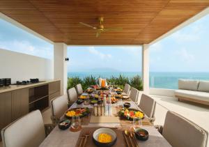 a dining room with a table with food on it at Cape Azure Resort Samui by Thalsea in Plai Laem