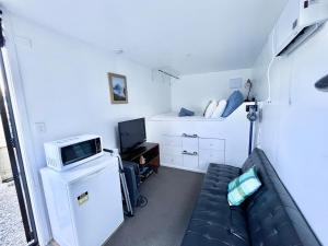 a small living room with a couch and a tv at The Bothy by the lake in Lake Hāwea