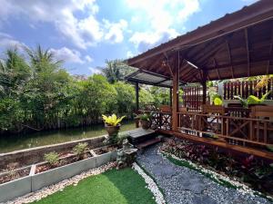 ein Garten mit einem Pavillon neben einem Fluss in der Unterkunft Doungploy BaanruenThai Homestay in Ban Hua Phrong
