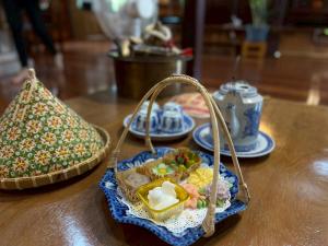 ein Tisch mit einem Korb voller Speisen und einer Teekanne in der Unterkunft Doungploy BaanruenThai Homestay in Ban Hua Phrong