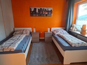 two beds in a room with orange walls at Ferienwohnung in Malente