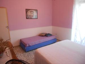 two beds in a room with pink and purple walls at Casa del Gelso Mortelle in Torre Faro