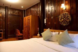 Ein Schlafzimmer mit einem Bett mit weißer Bettwäsche und Holzwänden in der Unterkunft Doungploy BaanruenThai Homestay in Ban Hua Phrong