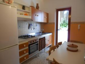 a kitchen with a sink and a stove and a table at Casa del Gelso Mortelle in Torre Faro