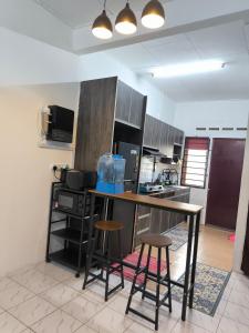 a kitchen with a counter and some stools in it at Homestay Idora PD in Port Dickson +4 photos