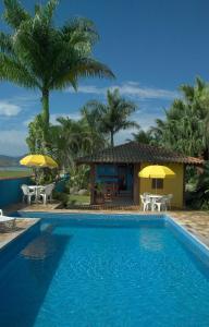a pool with chairs and umbrellas next to a house at Pousada Vistamar in Paraty