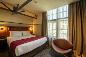 a hotel room with a bed and a chair and a window at NOBO - Hotel in old Tbilisi in Tbilisi City