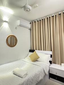 a bedroom with a bed with white sheets and a mirror at Snapstay103 in Hulhumale