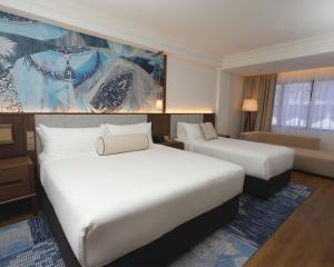 a hotel room with two beds and a couch at Perdana Kota Bharu in Kota Bharu