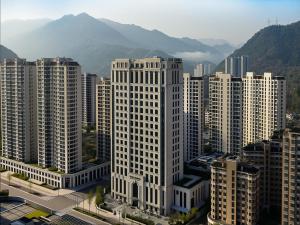a tall white building in a city with mountains at Four Points by Sheraton Qingtian in Qingtian