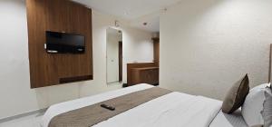 a bedroom with a bed with a tv on the wall at Hotel Glory in Bavla