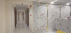 a hallway with a marble wall and a hallway with mirrors at Hotel Glory in Bavla