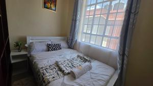 a bed in a small room with a window at Mina Luxe Machakos in Machakos