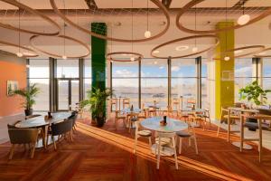 a restaurant with tables and chairs and large windows at ibis Styles Chisinau in Chişinău