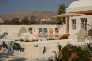 a white house with a swimming pool and a patio at Black Rose Beach Suites in Perivolos
