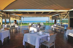 a restaurant with white tables and chairs and the ocean at Susesi Luxury Resort in Belek