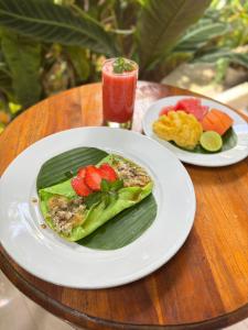 two plates of food on a table with a drink at Yessi House in Ubud