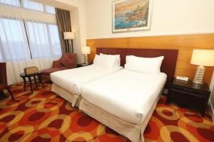 a hotel room with a large bed and a chair at Perdana Kota Bharu in Kota Bharu