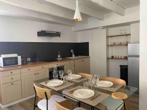 a kitchen with a dining table with plates and wine glasses at La Stracciatella Saint-Aignan in Saint-Aignan