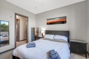 a bedroom with a large white bed with a painting on the wall at Upper Floor w Courtyard View 550 in Kelowna