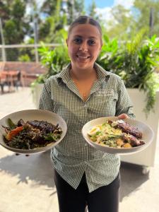 a woman is holding two plates of food at Amaroo Hotel Dubbo in Dubbo