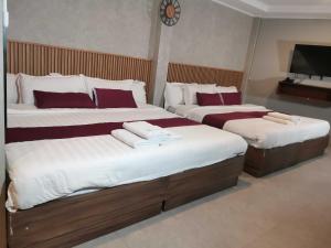 two beds in a hotel room with towels on them at Dancenter Airport Hotel - Grey Hotel in Pampang