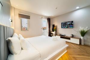 a white bed with white pillows in a bedroom at Golden Suites Saigon in Ho Chi Minh City