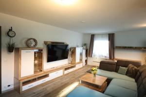 a living room with a couch and a flat screen tv at Wasser & Bergwelt Appartement Kärnten in Seeboden