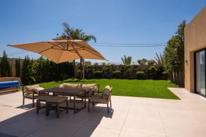a table and chairs with an umbrella on a patio at Villa prestige, terrain padel, salle de sport, hammam in Aït Amara el Ouled +105 photos