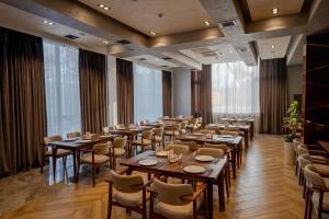 a restaurant with wooden tables and chairs and large windows at UNIQUE Airport Hotel in Tashkent