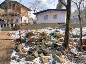 a pile of rocks in the snow in front of a house at The Cottage Depot in Bīr +11 photos