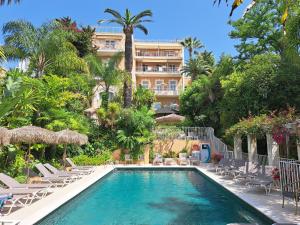 a swimming pool with chairs and a hotel in the background at Residence Veles Plage in Cannes